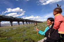Local residents look on as a train passes through the Qinghai-Tibet railway in Damxung county, Tibet, in this file photo
